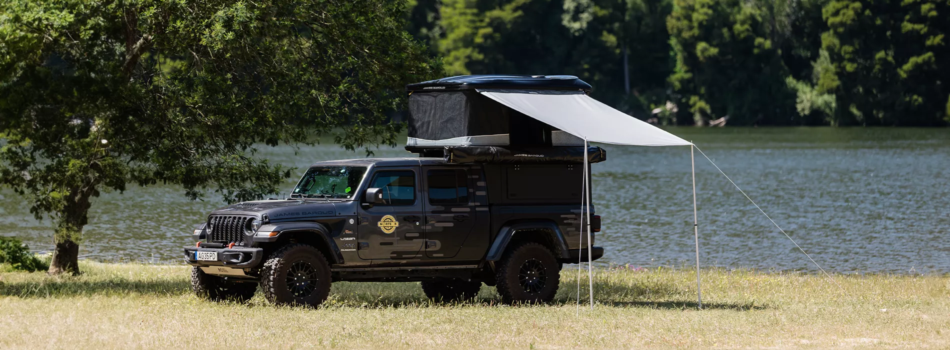 Frontier awning mounted on the open James Baroud Odyssey, with a beach in the background.