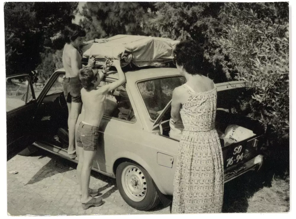 Mario and his brother tucking a tent on top of a car in the 60s